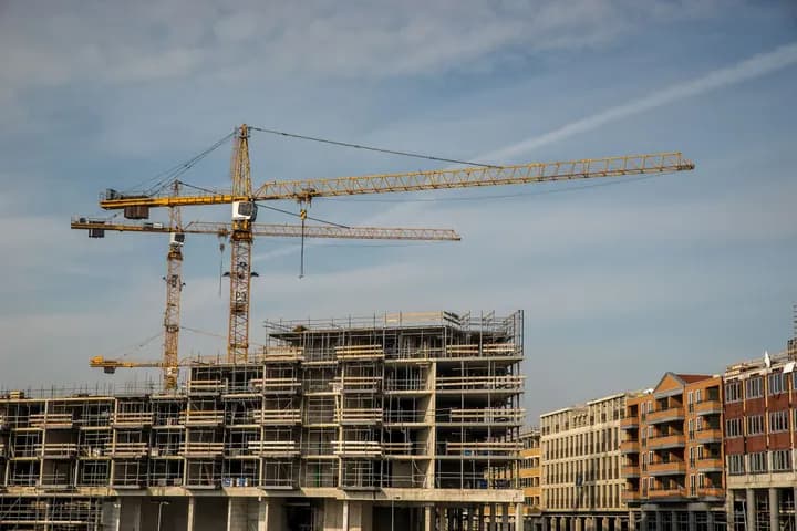 A concrete-frame building under construction with tower cranes